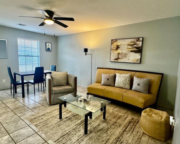 A living room with a sofa, coffee table, and a ceiling fan.