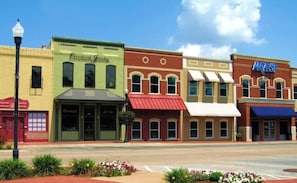 A row of commercial buildings with storefronts, including a bakery and a store with a blue awning.