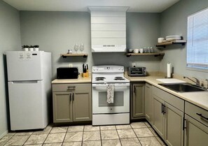 A kitchen with a refrigerator, stove, oven, and a sink.