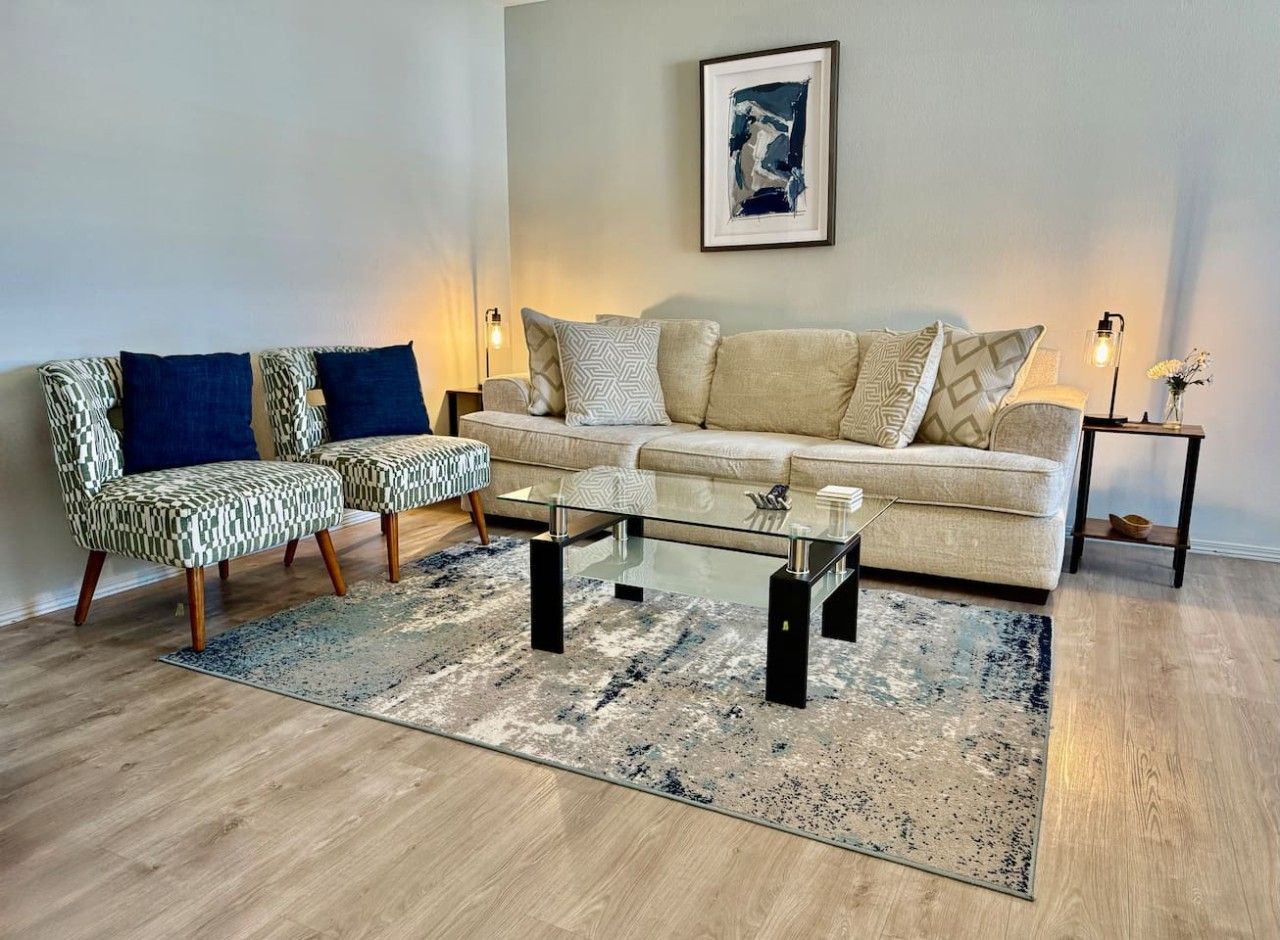 Un salon comprenant un canapé, deux fauteuils, une table basse et un tapis.