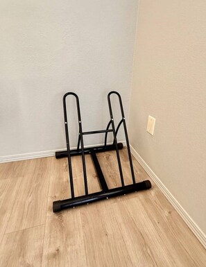 Una estantería metálica negra apoyada contra una pared con suelo de madera.