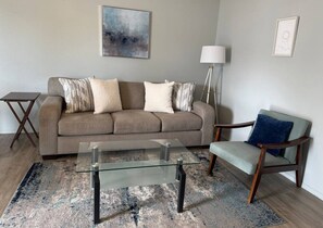 A living room with a sofa, a coffee table, a chair, a floor lamp, and a rug.