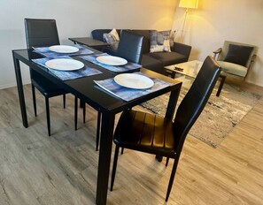 Un coin repas avec une table dressée pour quatre personnes, agrémenté d’un canapé et d’un fauteuil.
