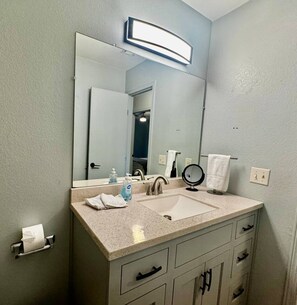 Une salle de bain équipée d’un meuble-lavabo à deux vasques, d’un grand miroir, d’un porte-serviettes et d’un support à papier toilette.