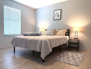 Une chambre à coucher avec un lit, des lampes de chevet, un tapis et une fenêtre avec des stores.