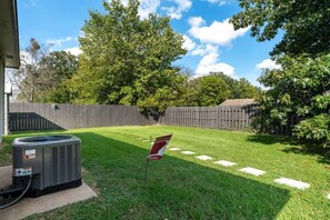 A backyard with a lawn, a wooden fence, and a flag.