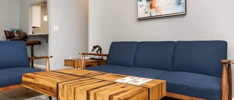 Un salon moderne avec un canapé bleu, une table basse en bois et une œuvre d’art abstraite accrochée au mur.