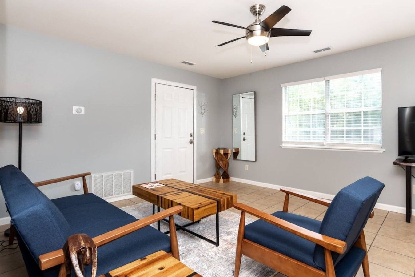 A living room with a ceiling fan, a TV, and a large window.