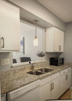A kitchen with a double sink, a microwave, and a pendant light.