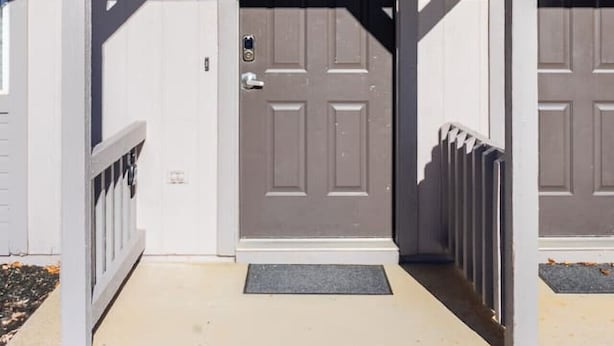 A two-car garage with a dark door, a small porch area, and a mailbox.