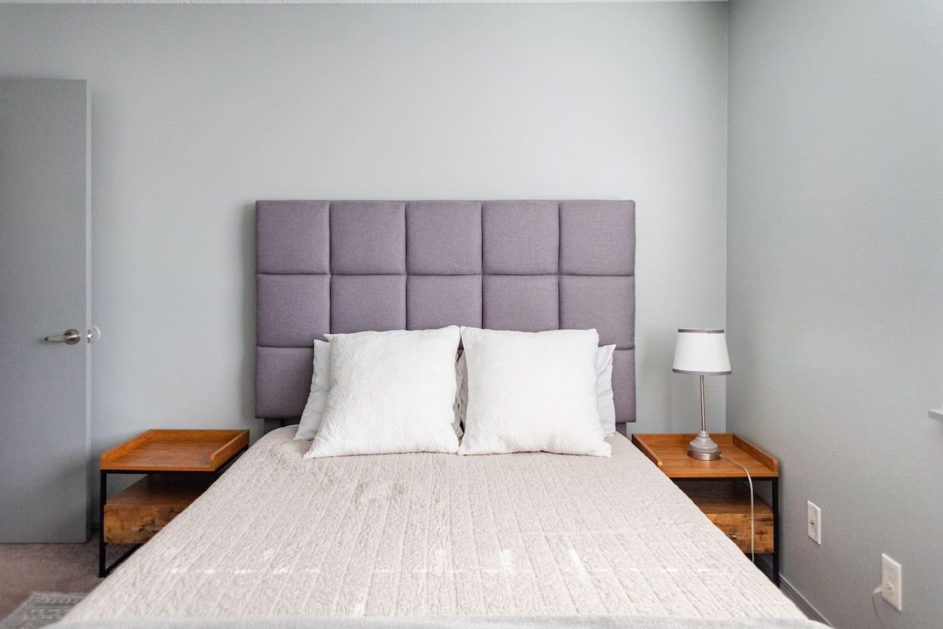 A bedroom with a bed, two nightstands, a lamp, and a door.