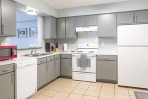 A modern kitchen with grey cabinets, a white stove, and a red microwave.