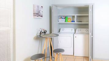 Un espace buanderie compact comprenant un lave-linge, un sèche-linge et une petite table avec des tabourets.