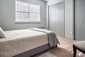 A bedroom with a bed, a window, a wardrobe, and a chair.