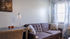 A room with a sofa, a table, a lamp, and a window with curtains.