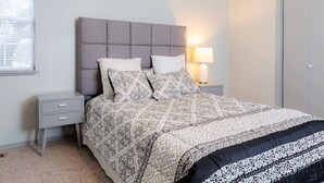A bedroom with a bed, nightstands, a lamp, and a wardrobe.