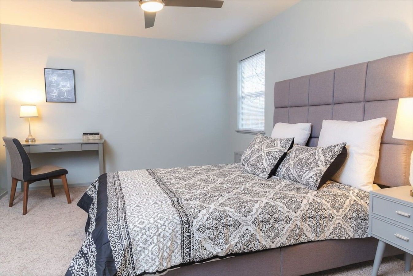 A bedroom with a bed, a desk, a chair, and a window.