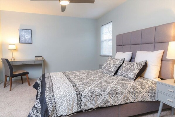 A bedroom with a bed, a desk, a chair, and a window.
