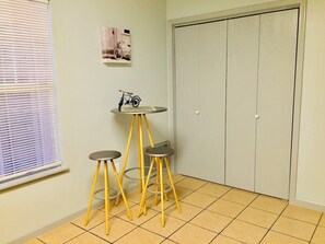 A room with a window, a door, and a small table with stools.
