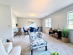 A living room with a sofa, chairs, a dining table, and a bookshelf.