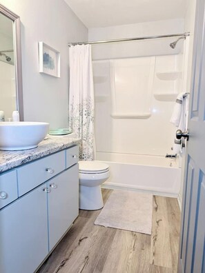 A bathroom with a bathtub, toilet, and a sink with a mirror.