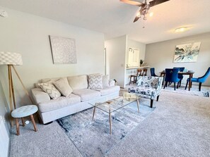 Sala de estar com sofá, mesa de centro e área de jantar com cadeiras.