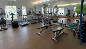 Kuntosali, jossa on juoksumattoja, painonnostolaitteita ja peiliseinä.