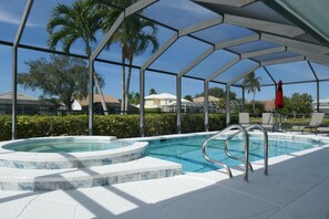 A covered swimming pool with a hot tub, surrounded by palm trees and a clear sky. - Beautiful Vacation Home with Saltwater Pool and Spa, Lake View and SW Exposure (Naples)