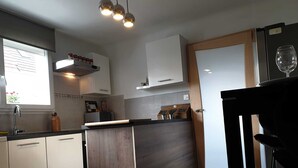 Et moderne køkken med en central ø, hvide skabe og en træbordplade.