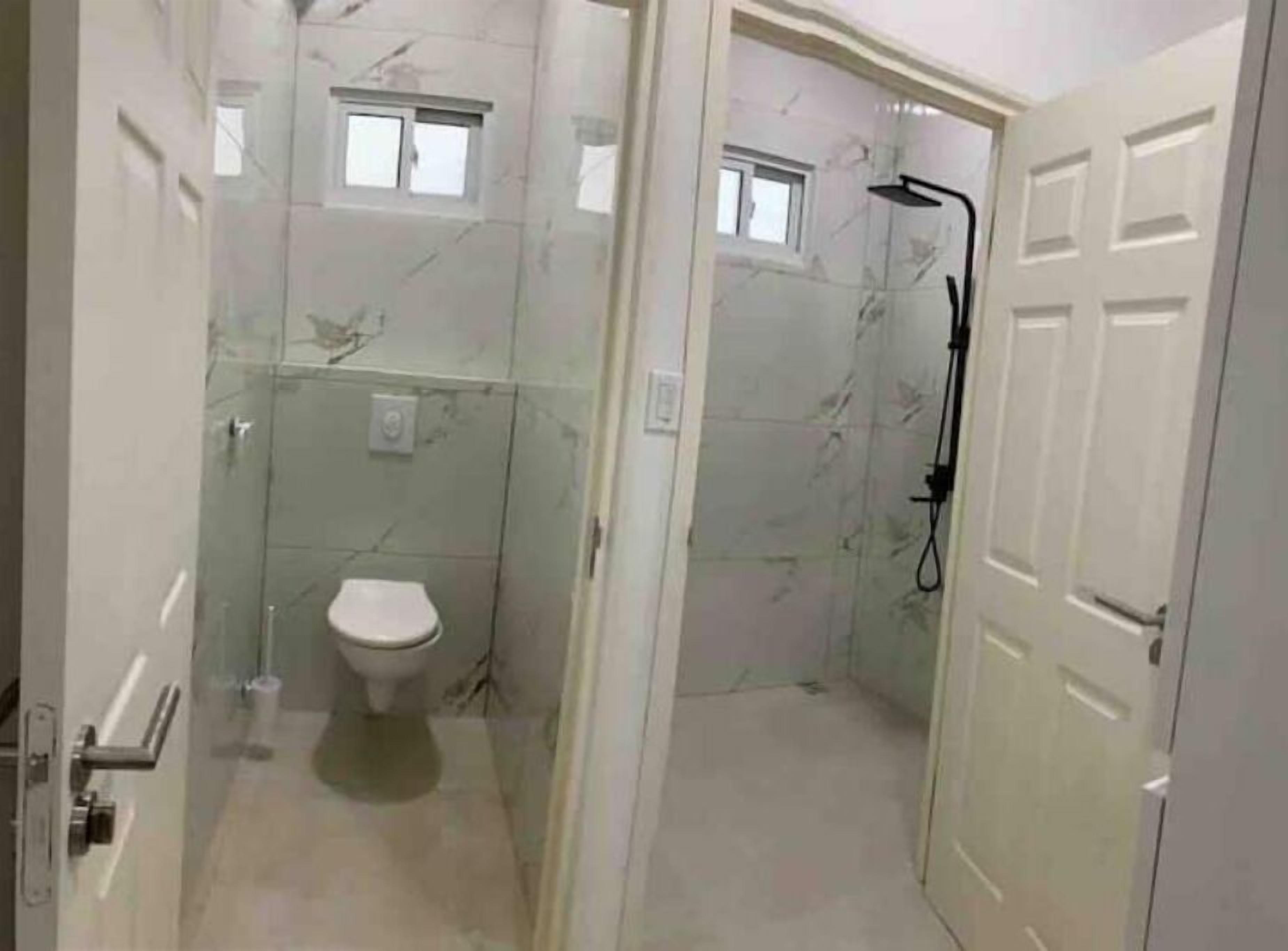 Een compacte badkamer met toilet, douche en raam.