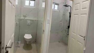 Een compacte badkamer met toilet, douche en raam.