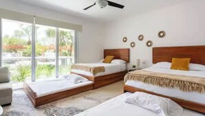 Ein Hotelzimmer mit zwei Betten, einem Deckenventilator und einem großen Fenster mit Blick auf Grünflächen.