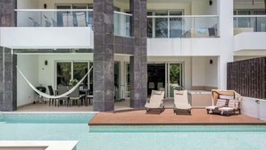 Ein modernes, zweistöckiges Gebäude mit Schwimmbecken, Außensitzgelegenheiten und einer Hängematte.