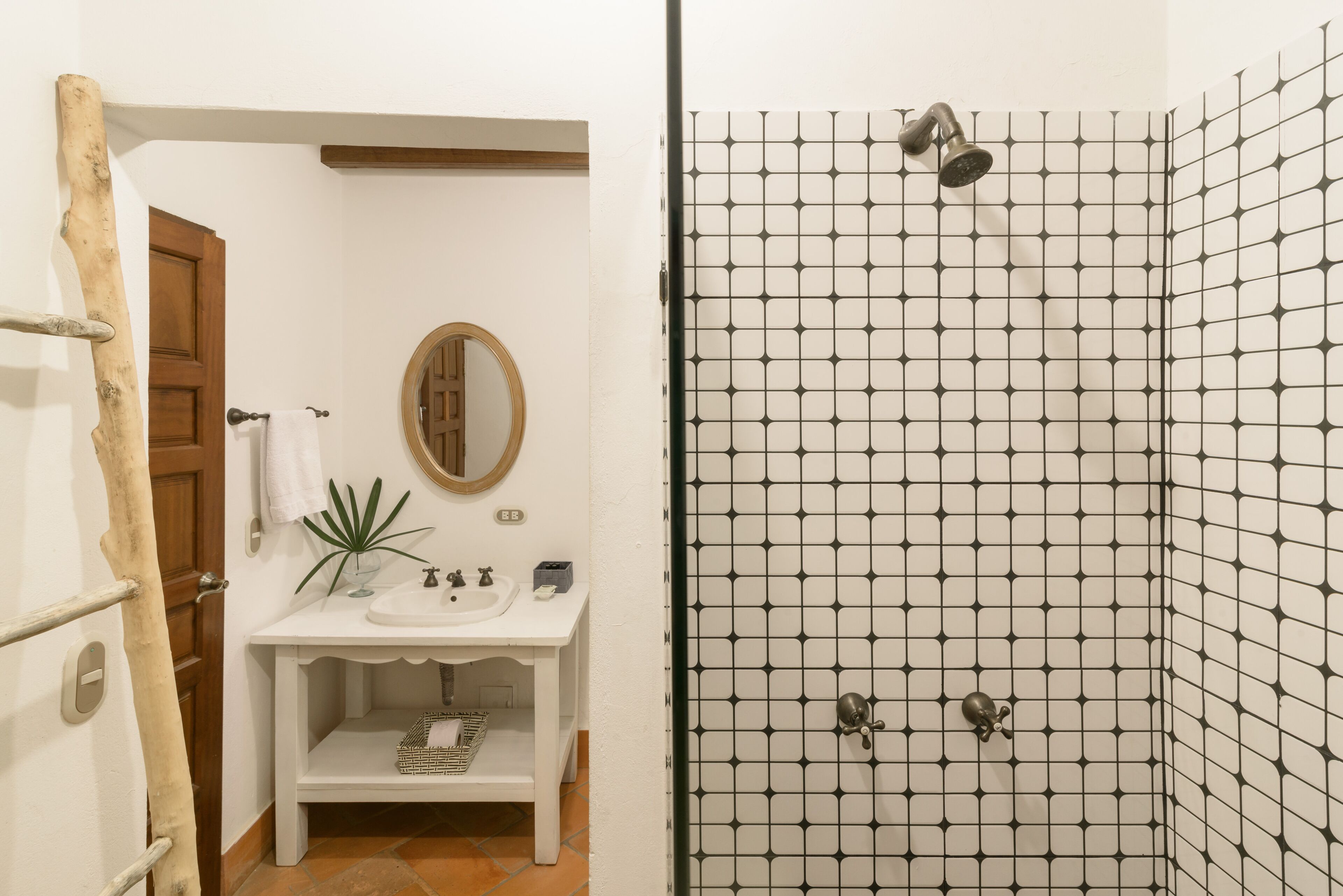 A bathroom with a white sink, mirror, and shower with a black grid pattern.