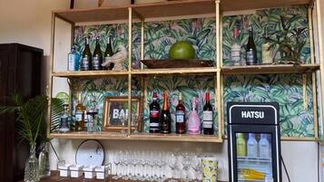 Een bar met drankflessen op de planken, een Hatsu koelkast en een spiegel boven de bar.