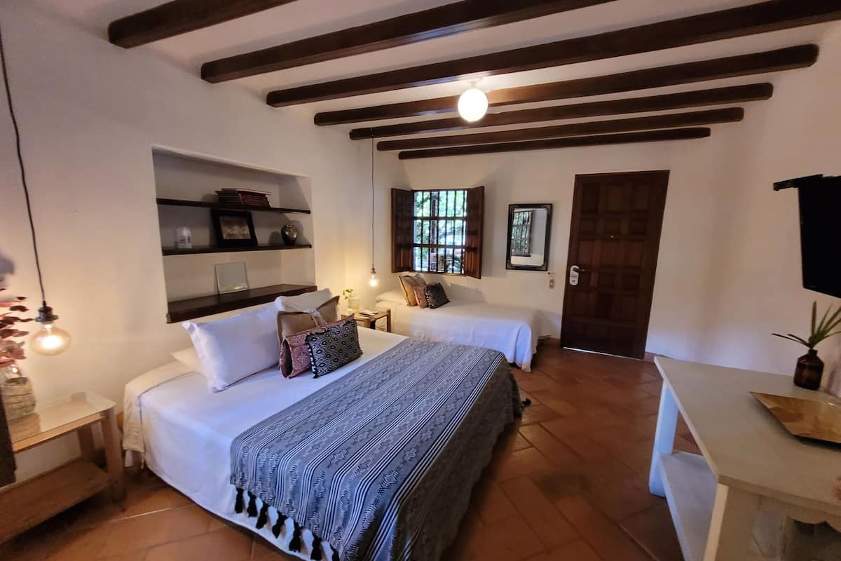 A bedroom with two beds, a desk, shelves, a window, and a door.