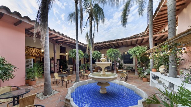 Un patio con una fuente, mobiliario exterior y plantas en macetas.