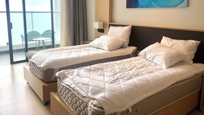 A hotel room with two beds, a balcony with a view, and a painting on the wall. - Cam Ranh Nha Trang Seaview Condotel (Bac Cam Ranh)