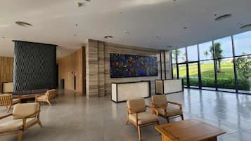 A spacious lobby with a large window, a modern art piece, and a seating area with wooden furniture.