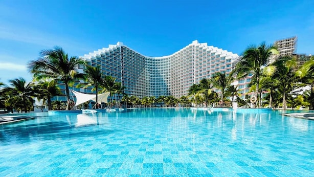 A large, clear swimming pool with a modern hotel building in the background. - Cam Ranh Nha Trang Seaview Condotel (Bac Cam Ranh)