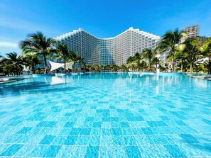 Une grande piscine aux eaux cristallines, avec un hôtel moderne en arrière-plan.