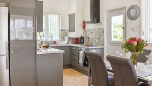 A modern kitchen with a central island, grey cabinetry, and a black range hood. - A beautiful bungalow overlooking the coastal town of Llanelli. (Llanelli)