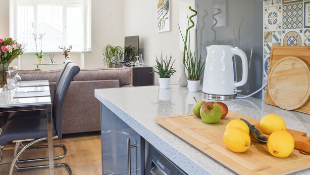 A modern kitchen with a dining area, a sofa, and a coffee maker. - A beautiful bungalow overlooking the coastal town of Llanelli. (Llanelli)