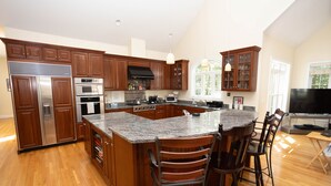 A modern kitchen with wooden cabinets, stainless steel appliances, and a large island with bar stools.