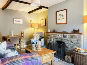 A cozy living room with a fireplace, wooden furniture, and framed pictures on the walls. - Escape to this wonderful holiday cottage in Helperby, North Yorkshire. (Helperby, near Thirsk)