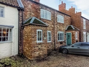 A traditional brick house with a green door, white windows, and a car parked in front. - Escape to this wonderful holiday cottage in Helperby, North Yorkshire. (Helperby, near Thirsk)