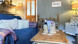 Una sala de estar acogedora con un sofá azul, una mesa de centro de madera y una estantería.