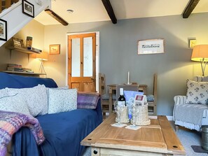 Ett mysigt vardagsrum med en blå soffa, ett träbord och en bokhylla.