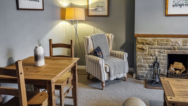 Una sala de estar acogedora con una mesa de comedor de madera, un sillón a rayas y una chimenea de piedra.