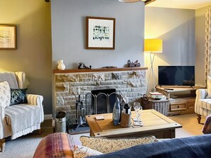 A living room with a fireplace, a television, and striped furniture. - Escape to this wonderful holiday cottage in Helperby, North Yorkshire. (Helperby, near Thirsk)